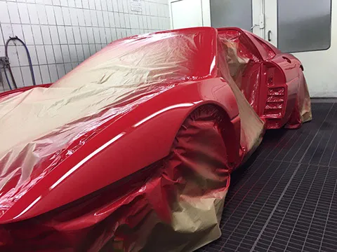 Frisch rot lackierter Ferrari, abgeklebt in der Lackierkabine